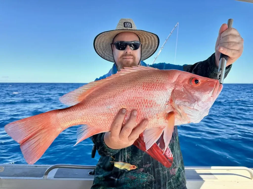 Angler from Akula Sportfishing in Port Douglas holding a large snapper-like fish on a boat