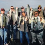 Group of anglers holding freshly caught salmon aboard an All Star Seattle Fishing Charters boat in Puget Sound.