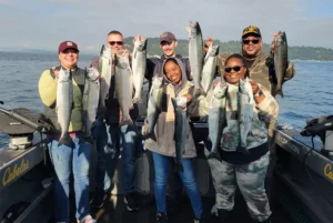 Group of anglers holding freshly caught salmon aboard an All Star Seattle Fishing Charters boat in Puget Sound.