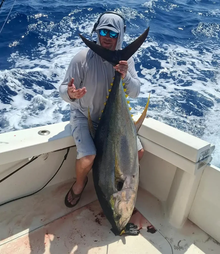 Angler holding a yellowfin tuna on a fishing boat offshore Cabo San Lucas
