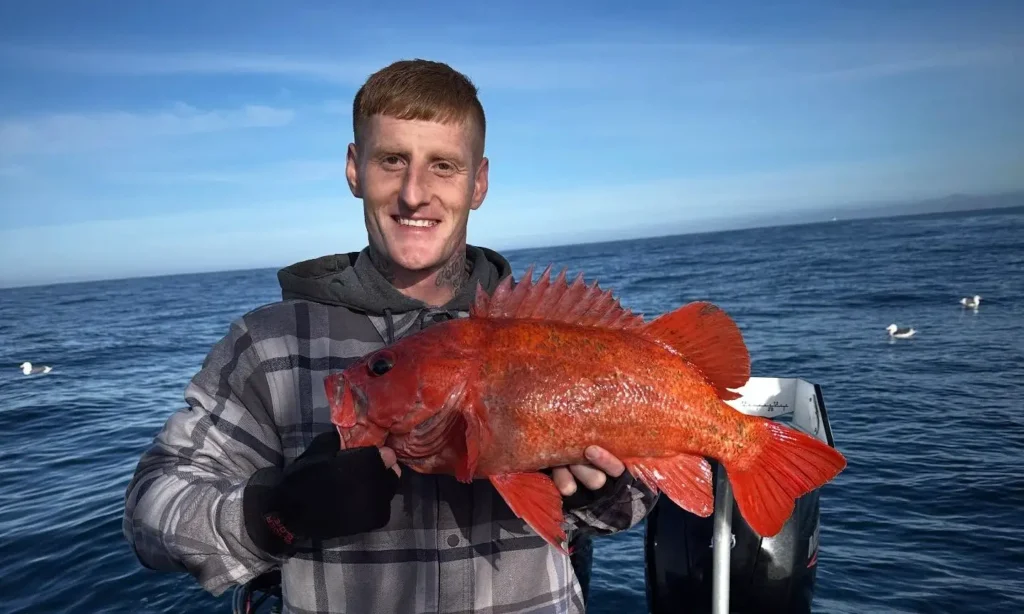 Angler holding a bright vermilion rockfish on a Crescent City Fishing charter