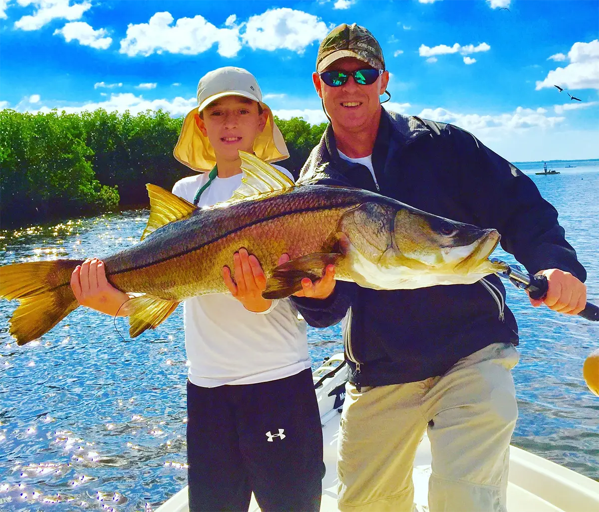 Adult and child holding a large inshore fish on a boat near Destin, Florida during a fishing charter