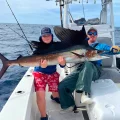 Anglers holding a sailfish aboard an offshore fishing charter, ALL IN Fishing Charters in Key West Florida