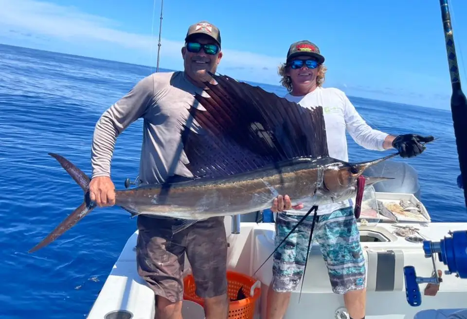 Two anglers holding a sailfish aboard a FishHawk Charters boat offshore St Petersburg
