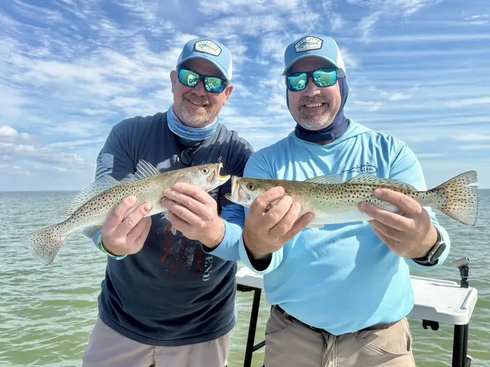 Two anglers holding speckled trout on a Florida Keys backcountry boat