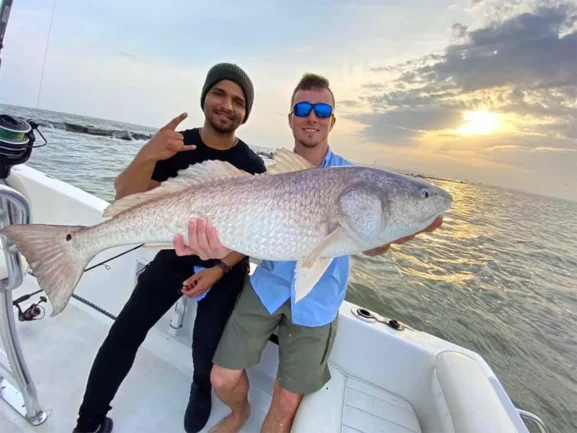 two men holding a large redfish on a boat in Galveston, Texas title