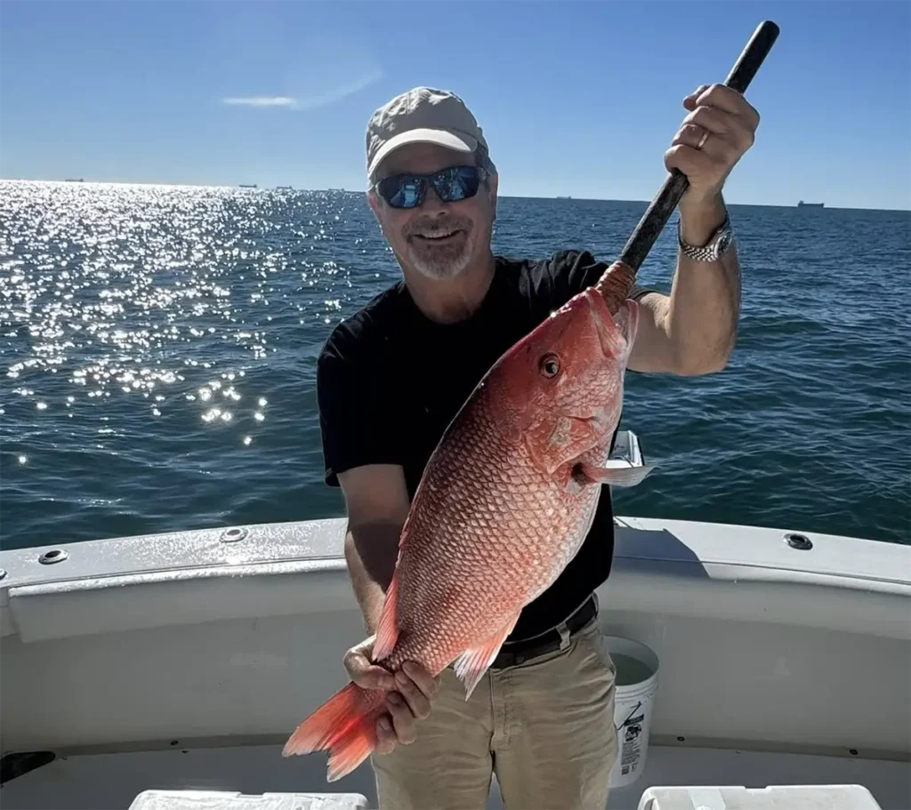 Angler holding a red snapper on an offshore fishing boat near Gulf Shores Alabama