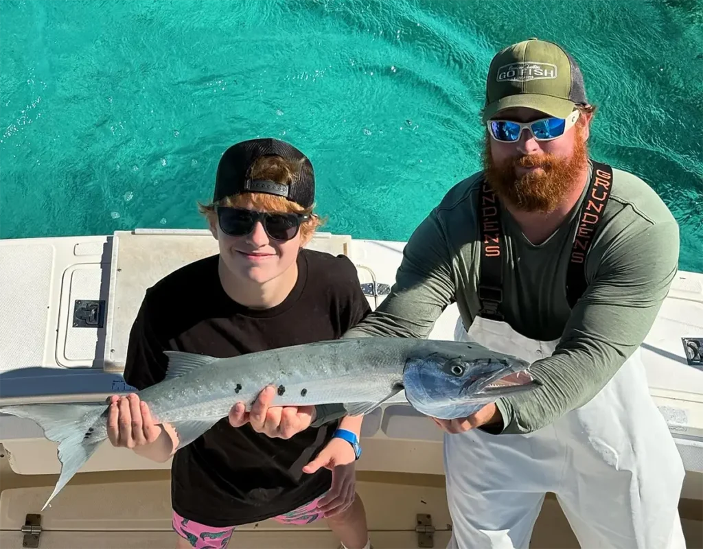 Two anglers in Islamorada holding a barracuda over turquoise water