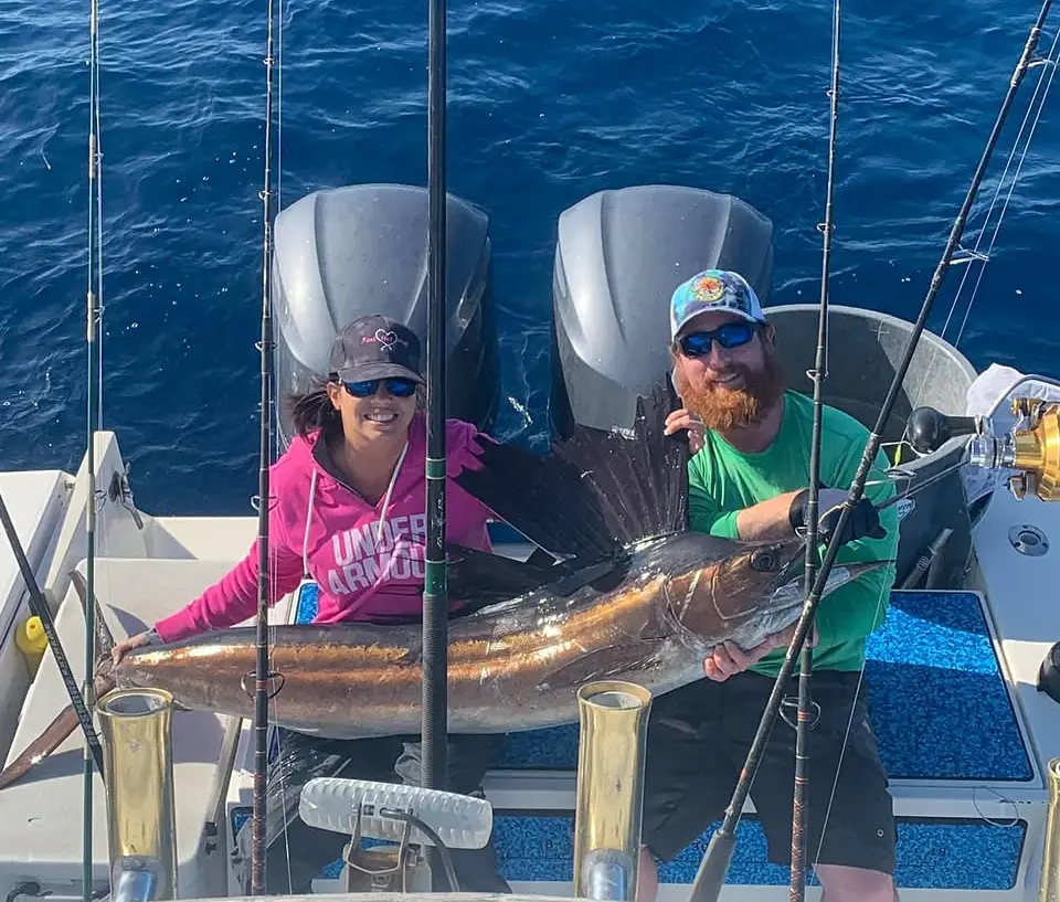 Two anglers holding a sailfish on the deck of an offshore fishing boat near Islamorada