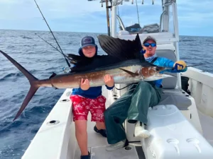 Anglers holding a sailfish aboard an offshore fishing charter, ALL IN Fishing Charters in Key West Florida