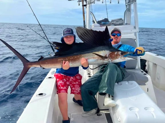 Anglers holding a sailfish aboard an offshore fishing charter, ALL IN Fishing Charters in Key West Florida