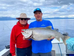 A monster sized Mackinaw trout being held up by Capt. Joby, next to the angler who caught it in South Lake Tahoe