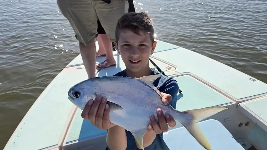 Young angler holding a small jack fish on a shallow water fishing boat near Naples Florida