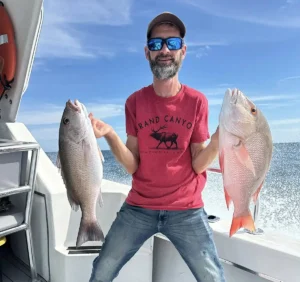 Angler holding two snapper on an offshore fishing boat near Naples Florida