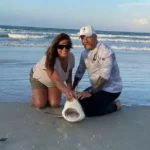 couple kneeling with a landed shark on New Smyrna Beach