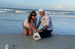couple kneeling with a landed shark on New Smyrna Beach