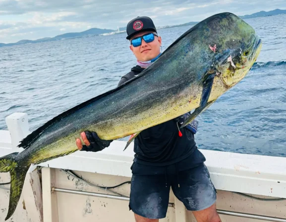 Angler holding a large mahi mahi on a fishing boat near Okinawa