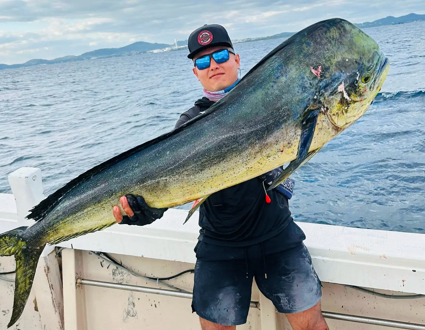 Angler holding a large mahi mahi on a fishing boat near Okinawa