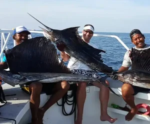 Group of anglers holding sailfish on a Phuket fishing boat during a clear day offshore