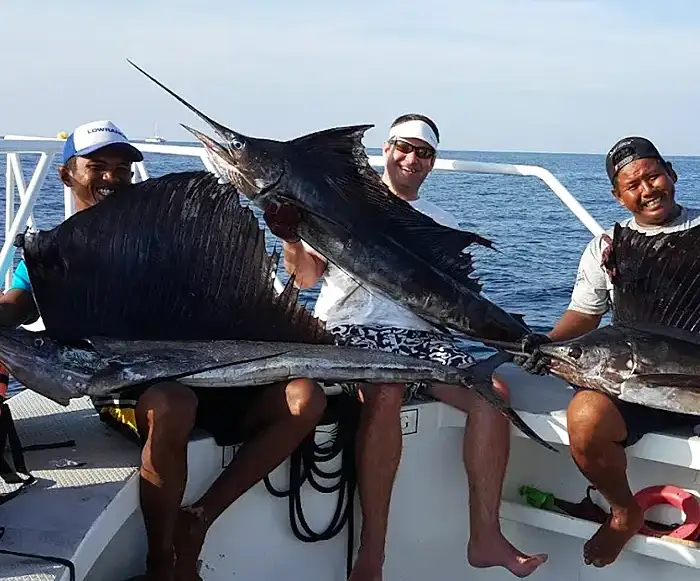 Group of anglers holding sailfish on a Phuket fishing boat during a clear day offshore