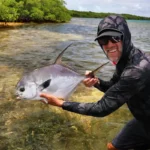 angler posing with a permit on the mangrove-lined flats of San Pedro Belize