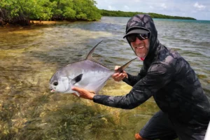 angler posing with a permit on the mangrove-lined flats of San Pedro Belize