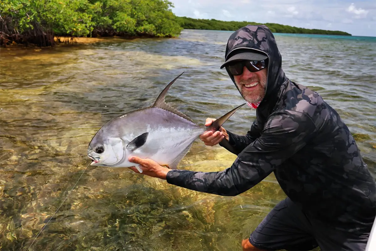 angler posing with a permit on the mangrove-lined flats of San Pedro Belize