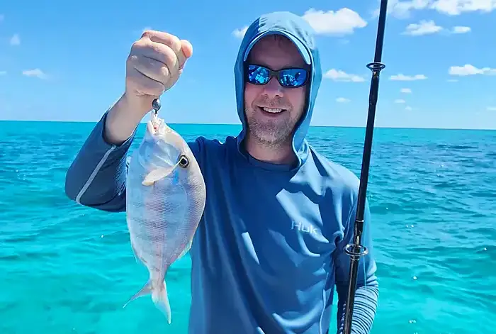 angler posing with a permit on the mangrove-lined flats of San Pedro Belize