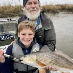 young angler holding a redfish with guide on a Savannah GA fishing charter