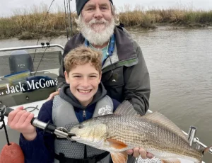 young angler holding a redfish with guide on a Savannah GA fishing charter