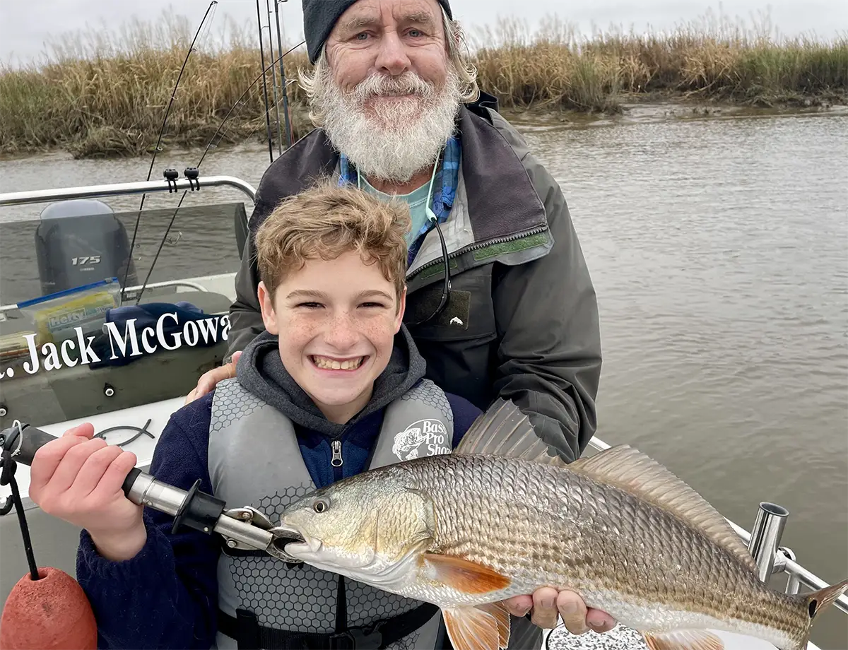 young angler holding a redfish with guide on a Savannah GA fishing charter