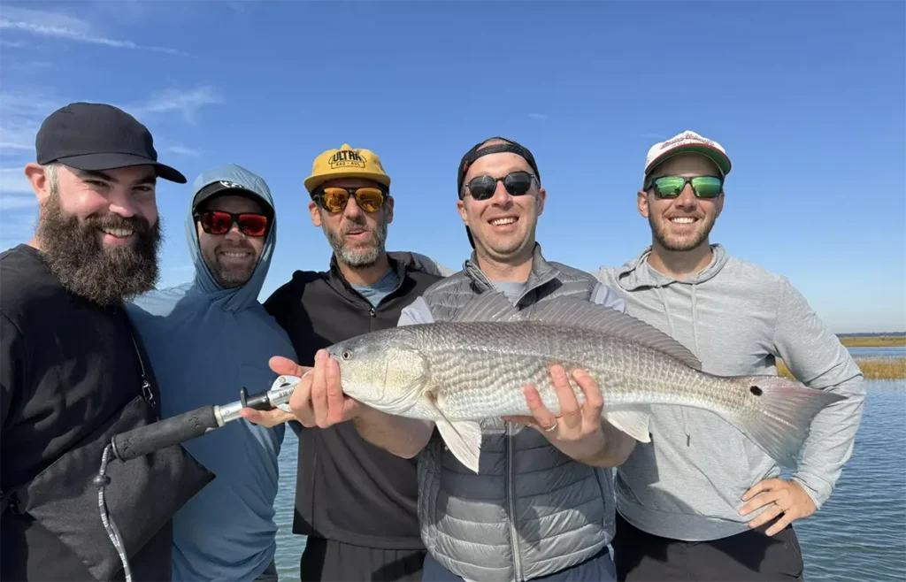 group of anglers holding a big redfish on a Savannah inshore fishing trip
