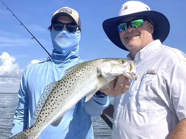 Anglers holding a speckled trout during an inshore fishing trip in Tavernier Florida Keys