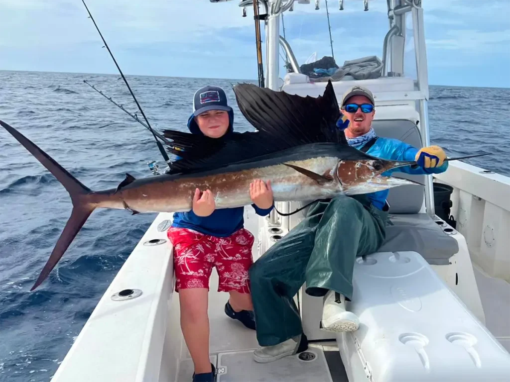 Two anglers holding a sailfish on a boat