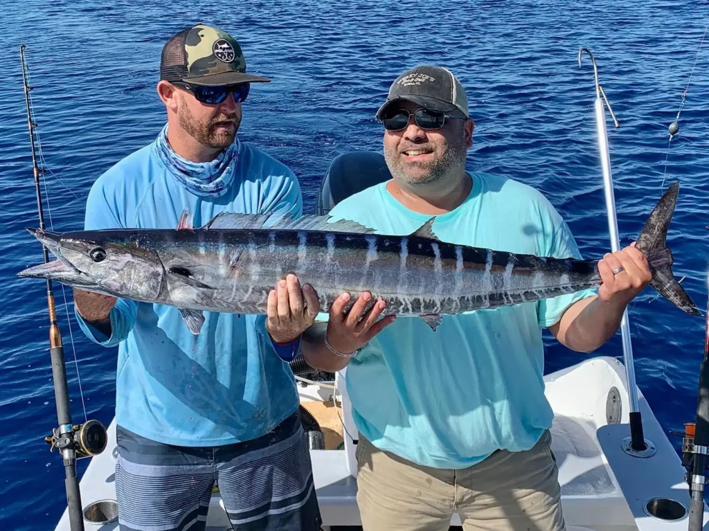 Two anglers holding a freshly caught wahoo during a fishing charter trip out of Cancun, MX