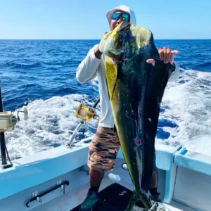 Angler holding a large mahi-mahi on a fishing boat in open ocean conditions